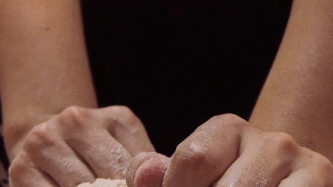 person holding white powder on brown wooden table