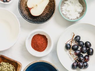 An overhead shot of fruits, seeds and spices in bowls