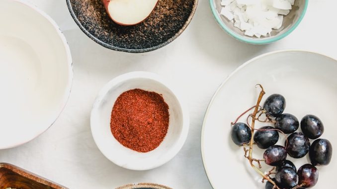 An overhead shot of fruits, seeds and spices in bowls