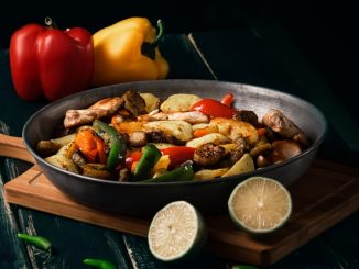 a pan filled with food sitting on top of a wooden cutting board