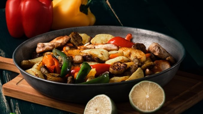 a pan filled with food sitting on top of a wooden cutting board