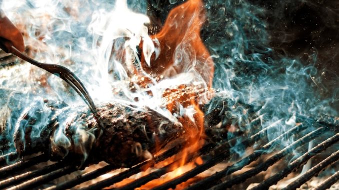 person cooking on grill with fire