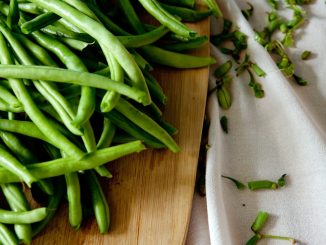 green peas on top of brown wooden chopping board