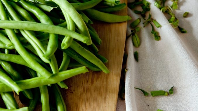 green peas on top of brown wooden chopping board