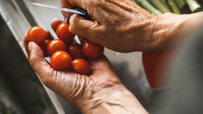 person holding knife and tomatoes