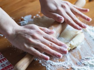 person holding dough on brown wooden table