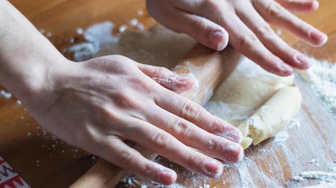 person holding dough on brown wooden table