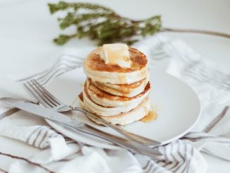 cooked pancake on round white ceramic plate beside butter knife and fork