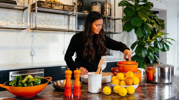 woman standing in front of fruits holding pot's lid