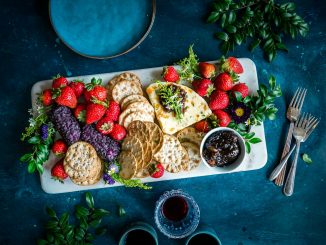 a platter of crackers, strawberries, and fruit