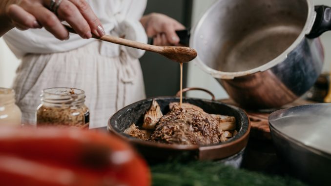 person holding brown wooden ladle