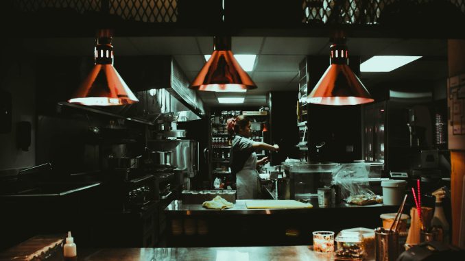 woman standing near three red pendant lamps