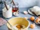 brown mixing bowl with eggs and flour with whisk