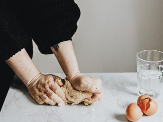 person in black long sleeve shirt holding brown chicken egg
