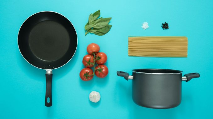 flat lay photography of frying pan beside tomatoes on blue surface