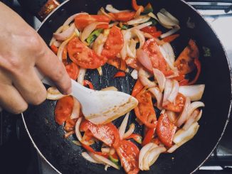 person holding black frying pan with cooked food