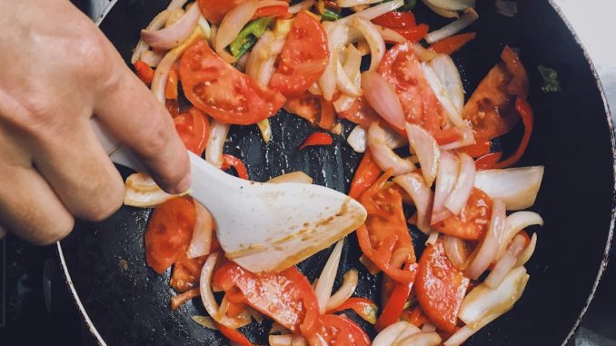 person holding black frying pan with cooked food